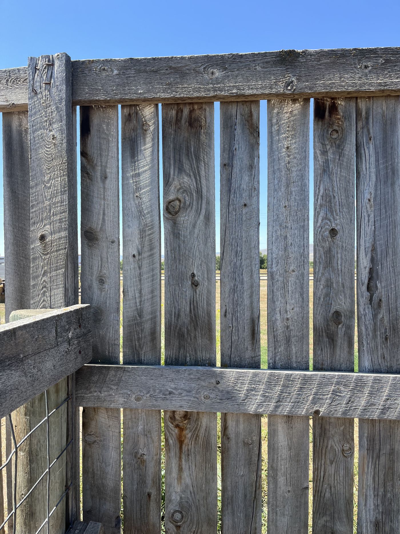 Weathered post-and-rail fence on a Bozeman property with the Gallatin Valley beyond